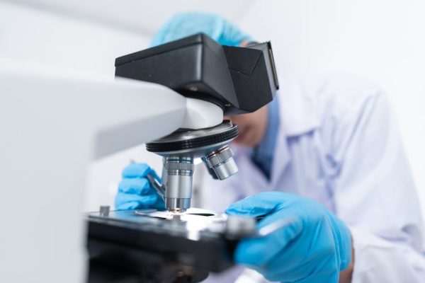 pexels-photo-3938022-3938022 Close-up of a scientist examining samples under a microscope in a lab setting.